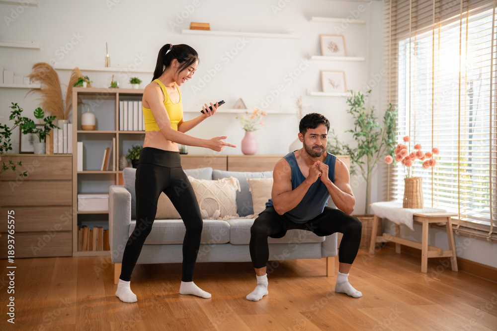 Obraz premium Woman coaching man during squat exercise at home