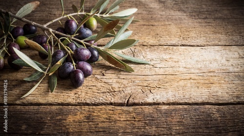 An exquisite olive branch, bearing a mix of dark and green ripe olives, lies delicately upon a weathered wooden surface, offering a rustic and natural backdrop.