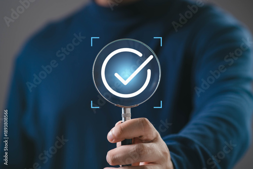 Magnifying glass highlighting a check mark icon, representing verification, approval, quality control, successful validation, compliance process, and confirmation of completed tasks.
