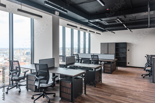 Open office interior with modern workstations and wood accents on floor. Panoramic view of open plan office with city skyline in background