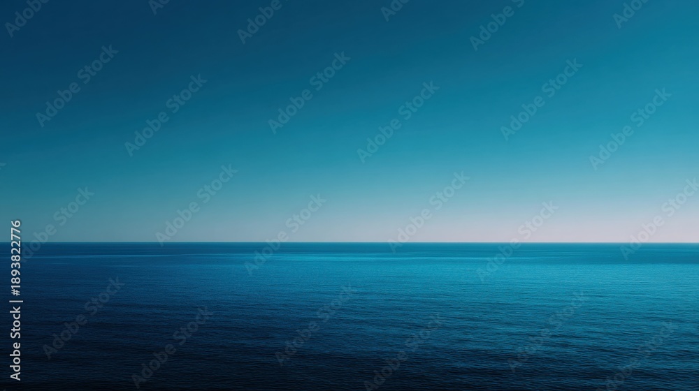 Obraz premium Photograph of the ocean. the sky is a deep blue color and the water is a lighter shade of blue. the horizon line is visible in the distance, and the horizon appears to be slightly blurred.