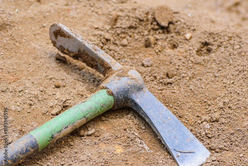 Quadro su tela Close up of pickaxe head lying on brown soil The Concept of Hard Work