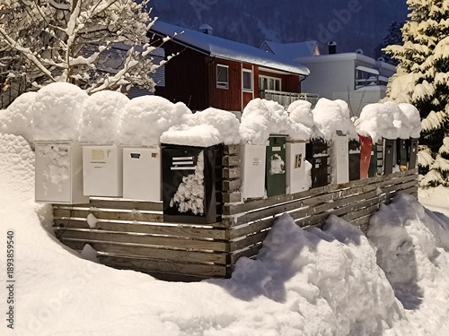 Briefkästen mit weißen Mützen und tief verschneite Straße im Winter zur Nacht