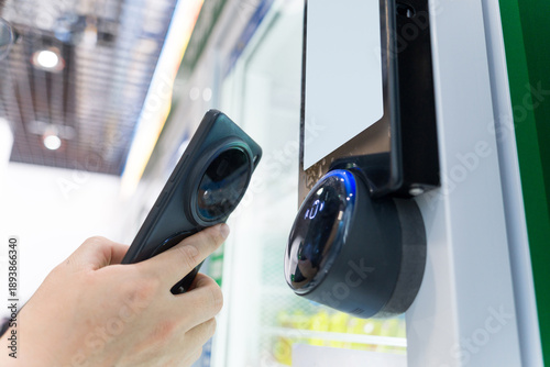 Foto Hand holding a barcode scanner aiming at a smart access control device for scann