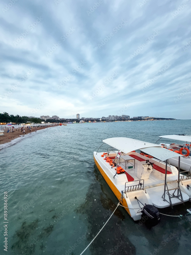 Fototapeta premium Small motorboat docked near beach under dramatic cloudy sky