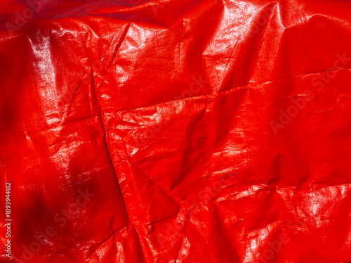 Red background. Red tarpaulin PVC background. Red aesthetic. Red plane surface. Wrinkle texture. Reusable material. Tarp backdrop. Polymer. Polyvinyl chloride. Durable material. PVC canvas. Red layout