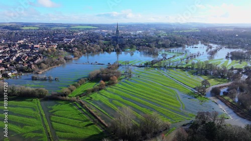 Tracking aerial shot of flooded meadows and Salisbury cathedral after Storm Chandra