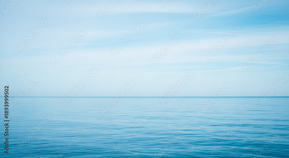Obraz premium Serene ocean landscape with calm waters under soft blue sky