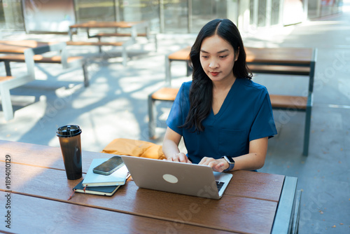 Female healthcare professional working on laptop outdoors
