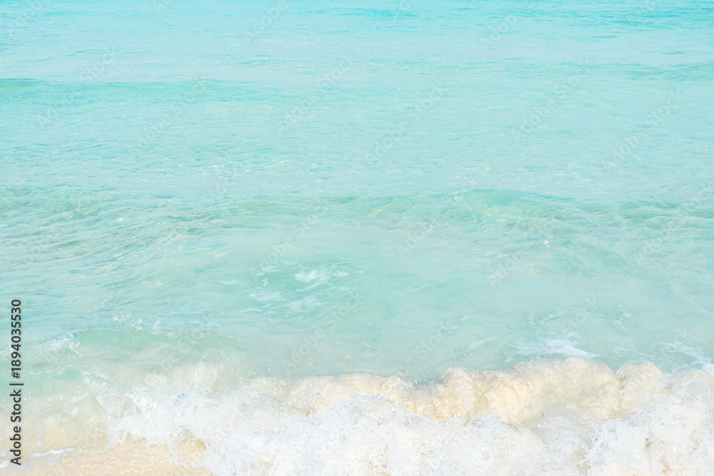 Obraz premium A sandy beach with clear turquoise water and small waves washing up on the shore