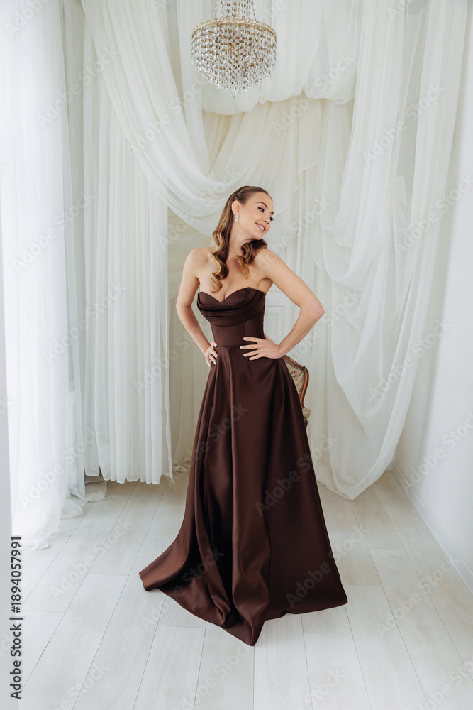 Fototapeta premium Portrait of an adult girl in a lush chocolate brown dress. Luxurious dresses for festive events and parties