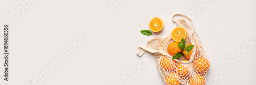 Obraz  z motywem Mesh string bag with ripe oranges on gray background flat lay top view. Concept of reusable bag for shopping, goods, and eco-friendly living. Zero waste. Background with citrus fruits