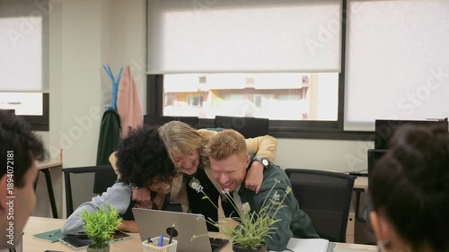 Mature businesswoman embracing colleagues after team success