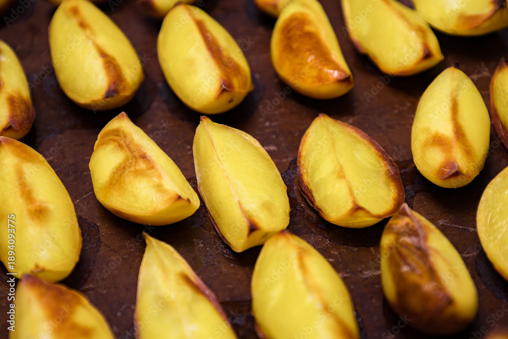 Obraz premium Baked yellow fruits arranged on a dark surface after cooking at a kitchen