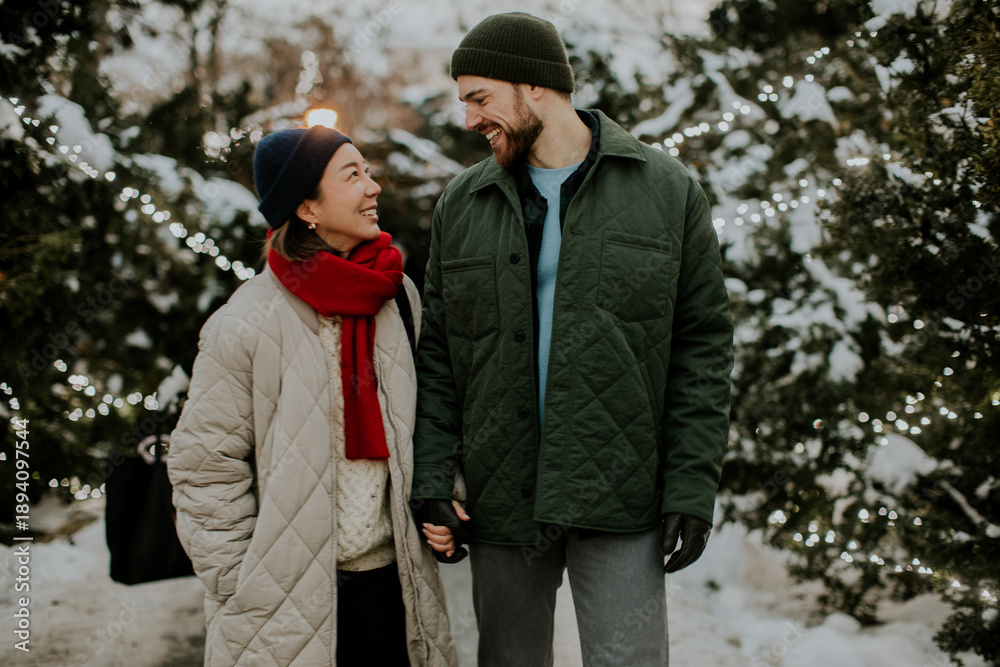 Fototapeta premium Couple enjoying a winter stroll amidst twinkling lights in a snowy park