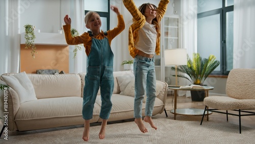 Fotografie Two happy Caucasian sisters children kids singing song jumping dancing listening