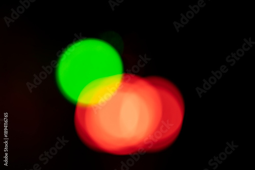 Abstract blurred red and green bokeh light circles on black background. Defocused abstract background photography. Optical blur and out of focus lighting concept. Design for poster, banner, wallpaper,