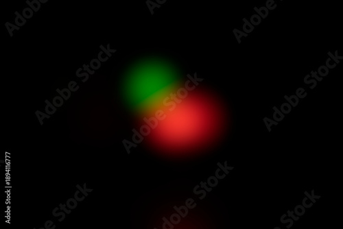 Abstract blurred red and green glowing light spots on black background. Minimal abstract background photography. Defocused light and optical effect concept. Design for poster, banner, wallpaper