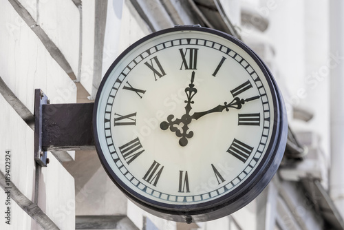 a clock on the wall of a building showing twelve o'clock, twelve minutes past