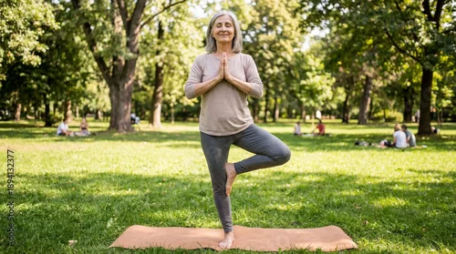 Fototapeta samoprzylepna Senior woman practicing yoga tree pose outdoors in sunny park, mindfulness meditation, healthy aging and relaxation concept, lifestyle fitness and balance exercise in nature