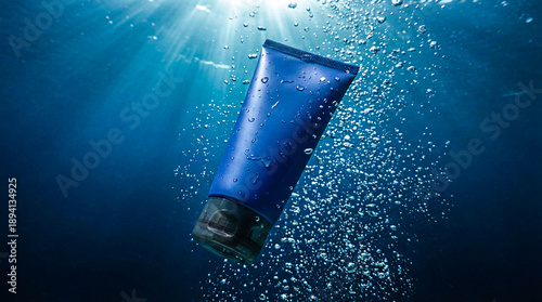 Blue tube of cosmetic product submerged underwater with sunlight shining through the water