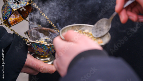 Foto Priest's hand adding incense to a smoking censer during an Orthodox church ritua