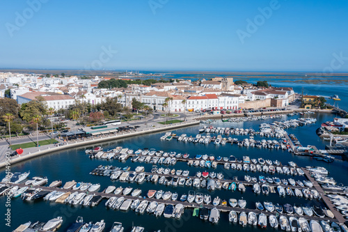 Faro in Algarve shows a busy dock with many boats. The old town stands in the background, showcasing typical architecture and clear blue skies