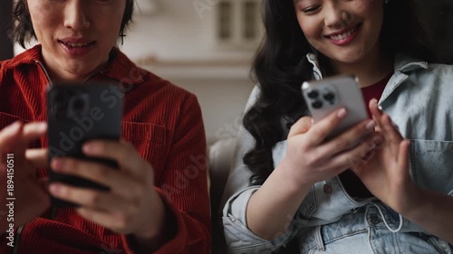 Happy Asian couple chatting on smartphones ignoring real life communication