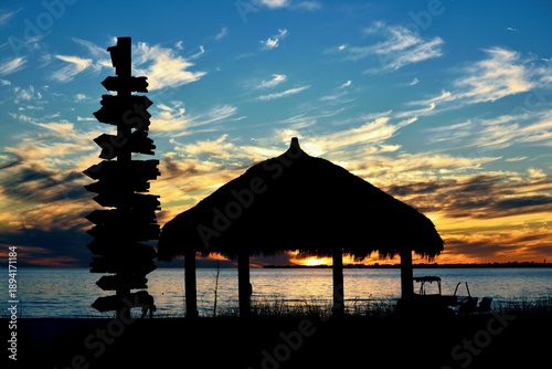 Fotografija A brilliant sunset glows against the silhouette of a tiki hut