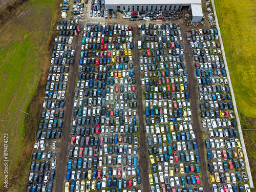 Large car salvage yard with numerous vehicles arranged in rows under a clear sky during daylight