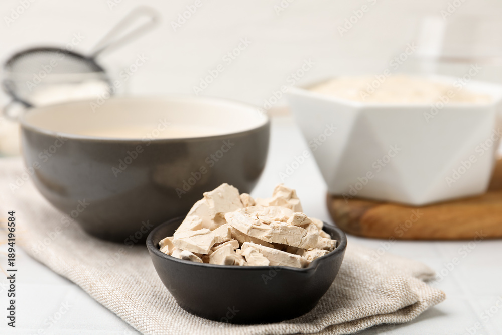 Fototapeta premium Yeast and dough on white tiled table, closeup
