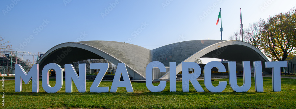 Fototapeta premium Iconic Monza Circuit entrance with modern curved architecture and bold signage, captured on a sunny day in Italy, symbolizing speed, motorsport heritage, and innovation.
