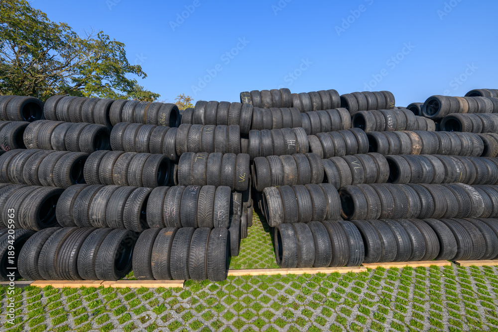 Obraz premium Stacked racing tires forming a safety barrier at Monza racetrack, Italy, under a clear blue sky, conveying speed, motorsport intensity, and track-side atmosphere.