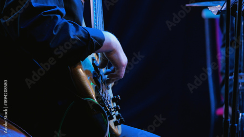 Tableau sur toile A close-up side view of a bass player's hands on the strings of a bass guitar