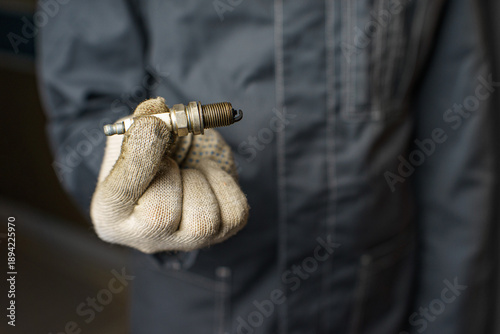A mechanic holds old spark plugs. Defective spark plugs, stained with motor oil. Soot on the spark plugs.