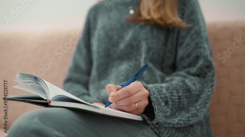 Woman sitting on a couch writing in a diary