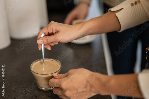 Tableau sur toile Woman's hands stirring coffee in clear glass cup