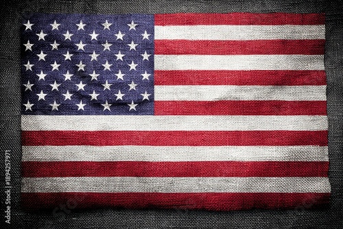 A textured representation of the American flag with red and white stripes and blue field filled with white stars. The fabric appears worn and rustic.