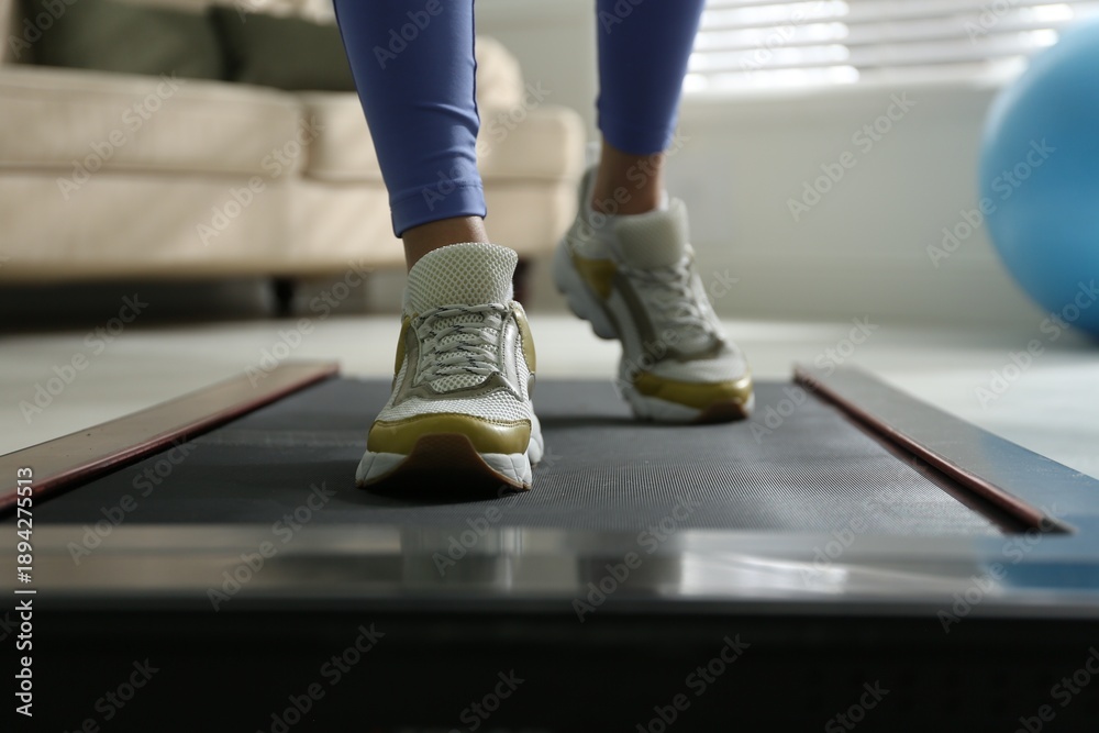 Fototapeta premium Woman training on walking treadmill at home, closeup