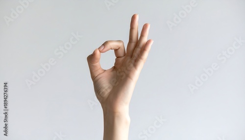 Female hand making okay gesture against clean background expressing approval and positivity