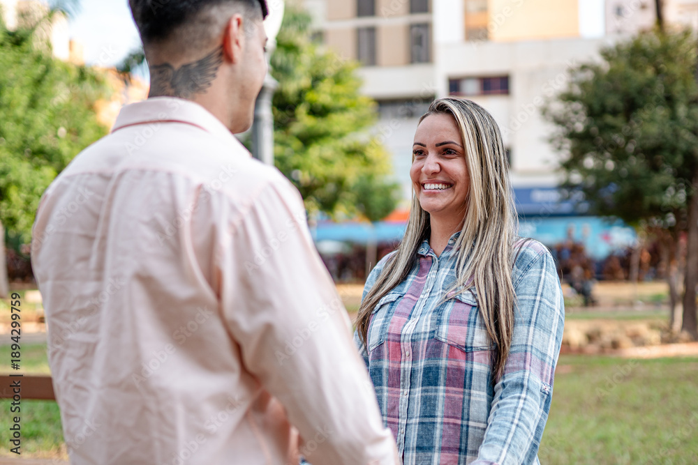 Fototapeta premium Happy young woman smiling while looking at her partner during a romantic date in a city park.
