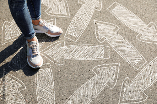 Canvastavla Woman in sneakers standing on road with arrows pointing in different directions, closeup