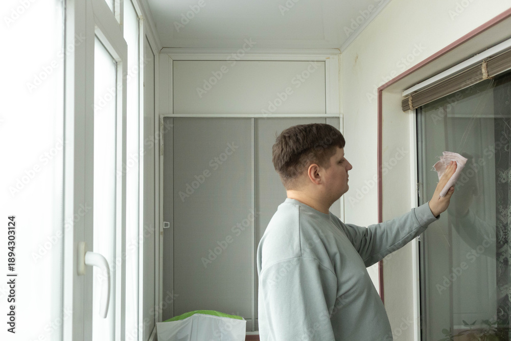 Fototapeta premium Man cleans window on balcony in a residential space during daytime