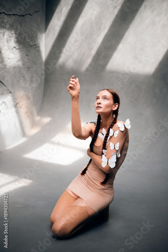Φωτογραφία Model poses with butterflies on skin while raising hand in a studio setting duri