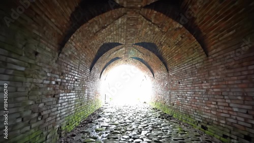 Light at end of old brick tunnel, representing an escape or new beginning journey through a historic path