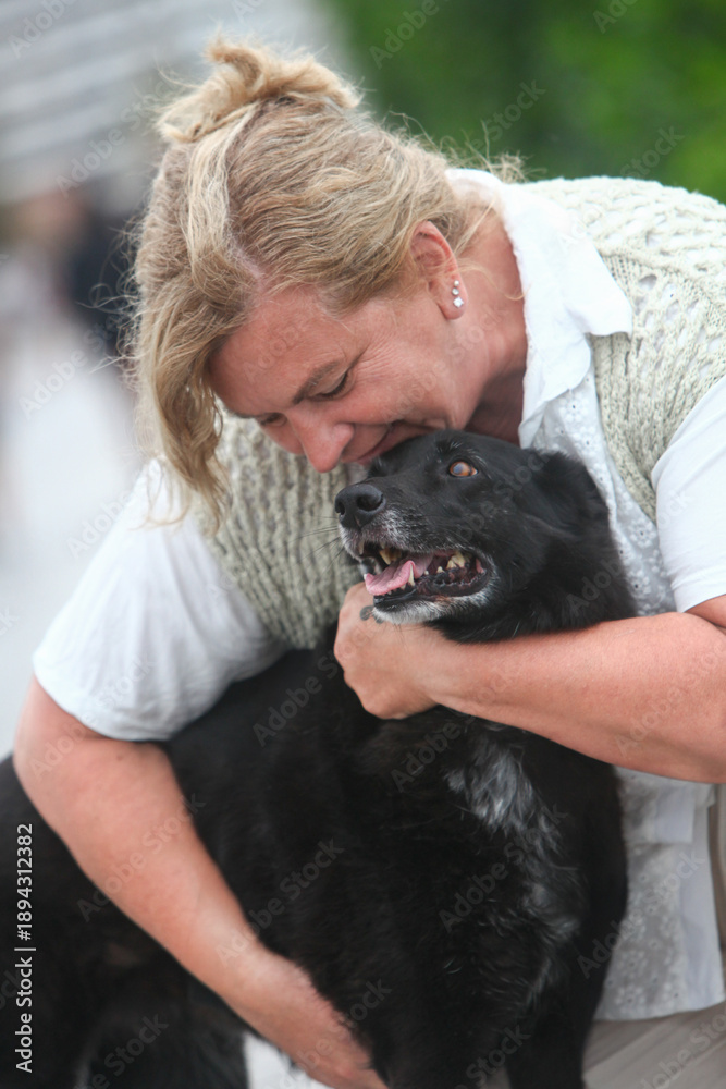 Obraz premium Portrait of a mature woman and her dog sharing a loving moment outdoors, showing mutual affection and companionship.
