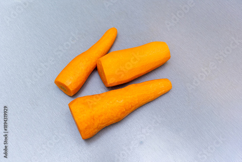 Three peeled fresh carrots on gray background