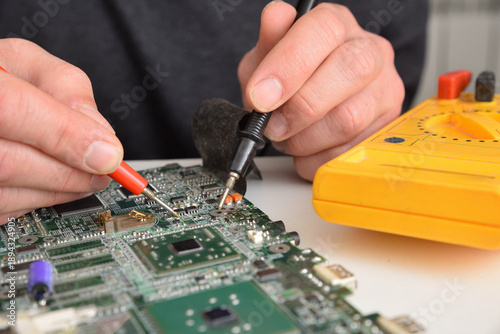 Fotografia Man testing printed circuit board with multimeter