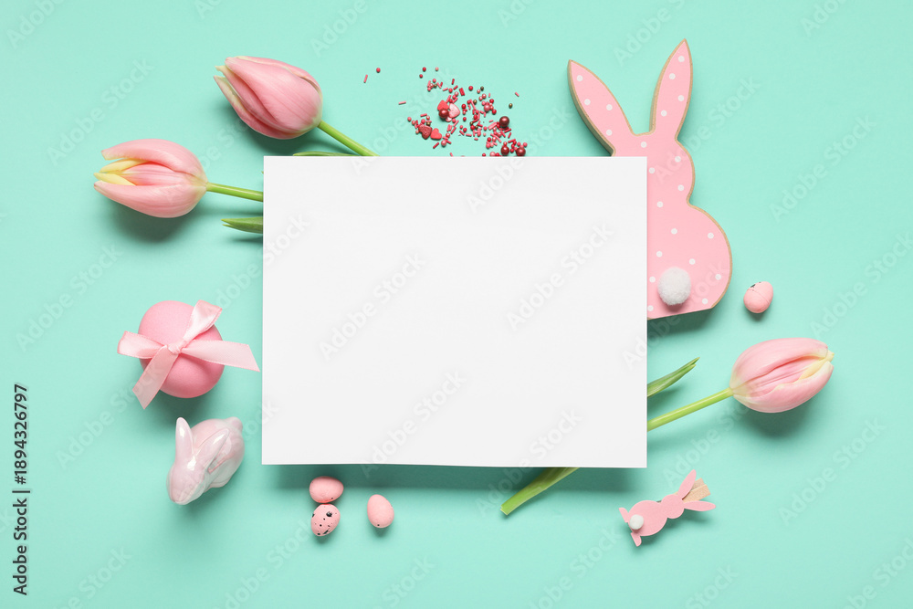 Naklejka premium Composition with blank card, Easter eggs, decorative bunnies and tulip flowers on turquoise background