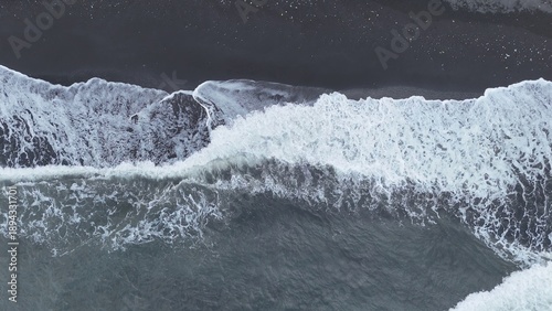 Dramatic Aerial View of Powerful Ocean Waves Crashing on a Black Sand Beach